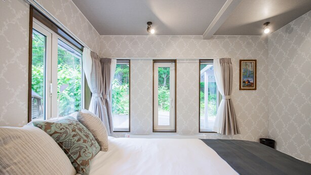 Un dormitorio con una cama grande, varias ventanas y vistas al exterior.
