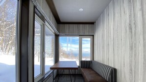 Una habitación moderna con ventanas amplias, un banco de madera y una mesa.