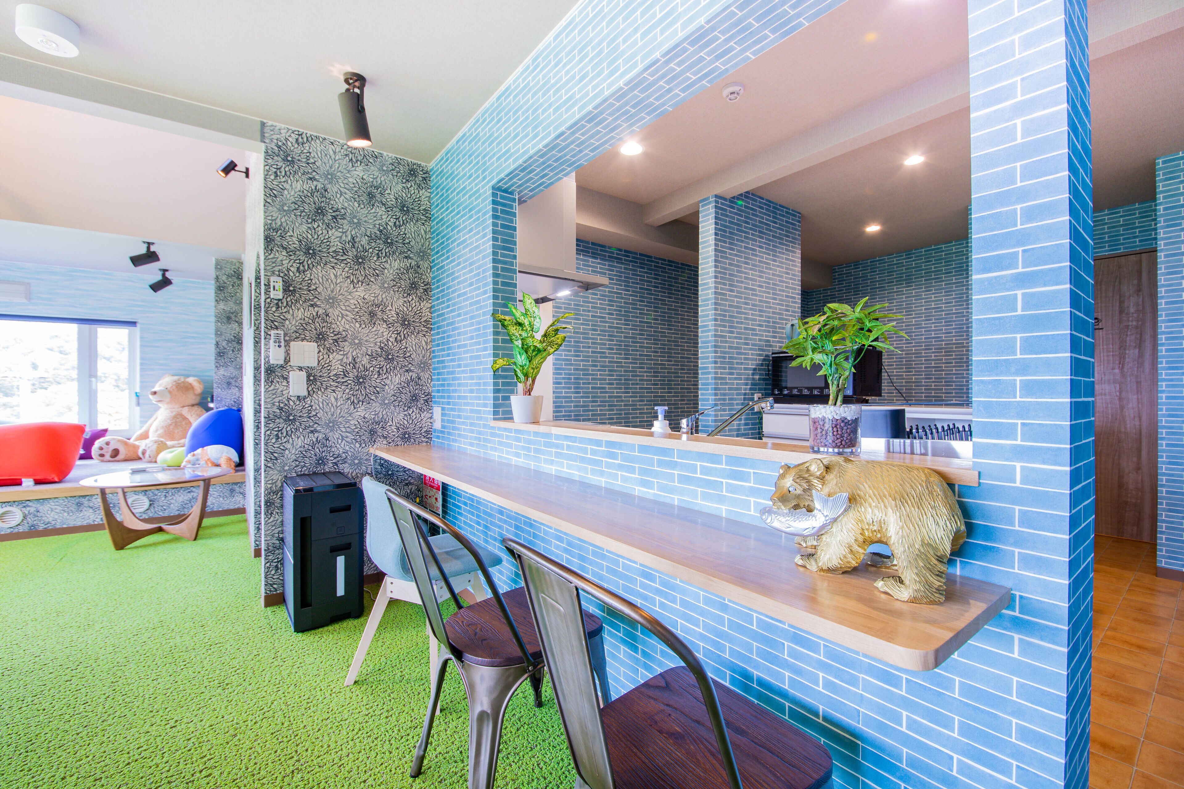 Ein modernes Interieur mit einer blauen Fliesenwand, einer Holztresen und einer kuscheligen Bärenstatue.
