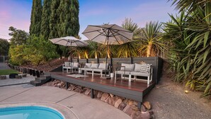 A poolside area with a built-in seating area, a pool, and surrounding greenery. - MCM Retreat w/ Pool & Spa | Lush, Quiet, Central (Spring Valley)