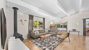 A modern living room with a fireplace, sofa, coffee table, and a view of a pool. - MCM Retreat w/ Pool & Spa | Lush, Quiet, Central (Spring Valley)