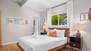 A bedroom with a bed, a nightstand, a lamp, a window with curtains, and wall art. - MCM Retreat w/ Pool & Spa | Lush, Quiet, Central (Spring Valley)