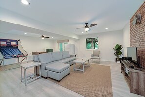 Uma sala de estar com sofá seccional, mesa de centro, mesa de bilhar e televisão.