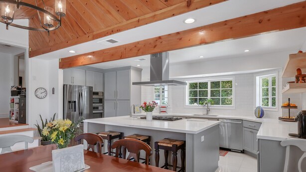 A modern kitchen with a large island, wooden ceiling beams, and a view of the outdoors through large windows. - Stylish San Fernando Stay with Designer Kitchen Upgrade (San Fernando)