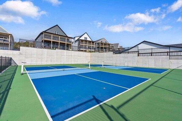 A tennis court with a net, surrounded by a concrete wall and a metal fence.