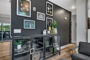 Una sala moderna con una pared oscura, una mesa consola de cristal y un sofá negro.