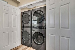 A laundry room with two front-loading washing machines and a dryer.