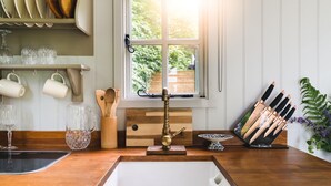 A kitchen with a wooden countertop, a white sink, and a window with a view of greenery. - Red Deer Escape - Luxury Cottages (Minehead)