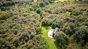 An aerial view of a rural property with a large house surrounded by dense vegetation and rolling fields. - Hooting Owl Retreat - Luxury Cottages (Minehead)