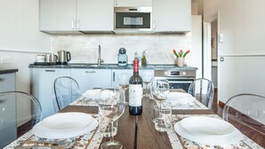 A dining table set with white plates, wine glasses, and a bottle of wine. - Your Home in Florence next to the central train station (Firenze)