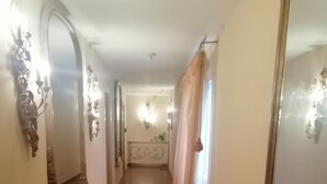A hallway with wooden flooring, a bench, and a large mirror on the right. - Your Home in Florence next to the central train station (Firenze)