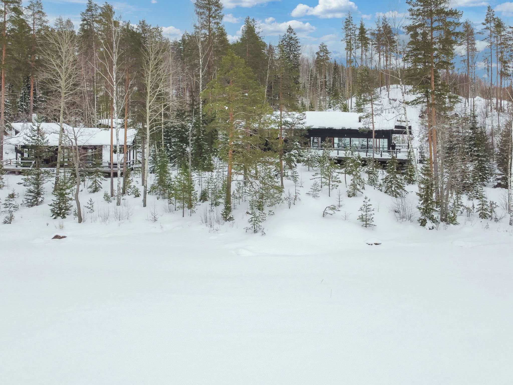 A snow-covered lodge surrounded by tall pine trees.