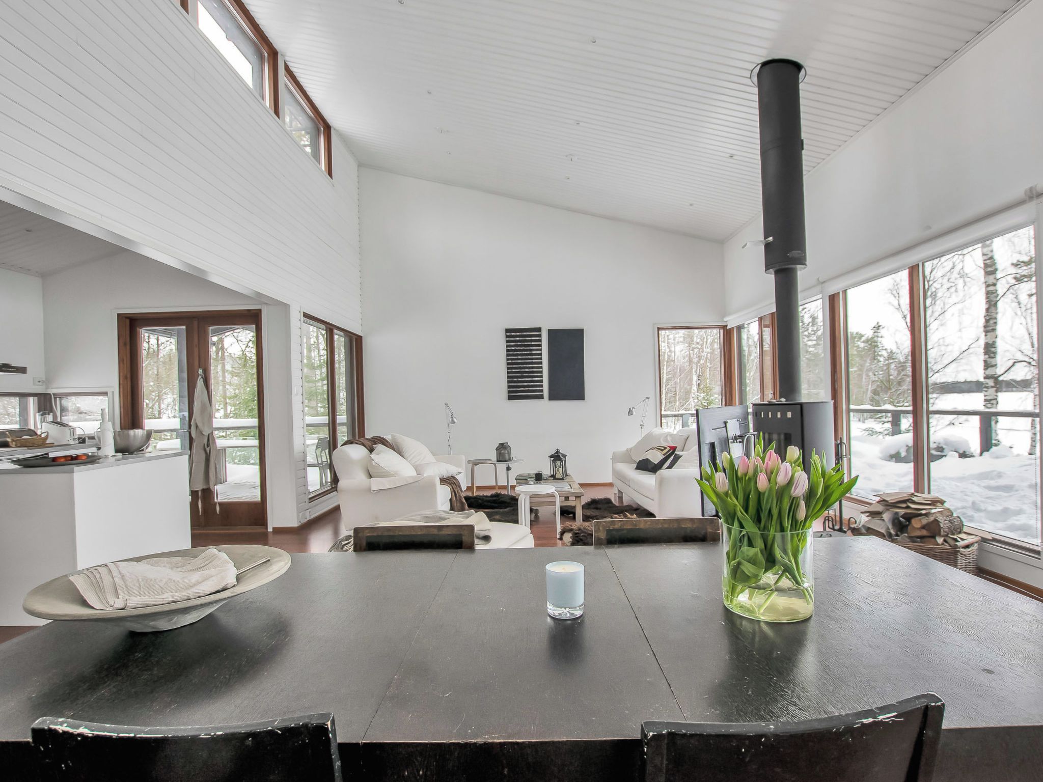 A spacious living area with a fireplace, a dining table with chairs, and a view of the snowy outdoors through large windows.