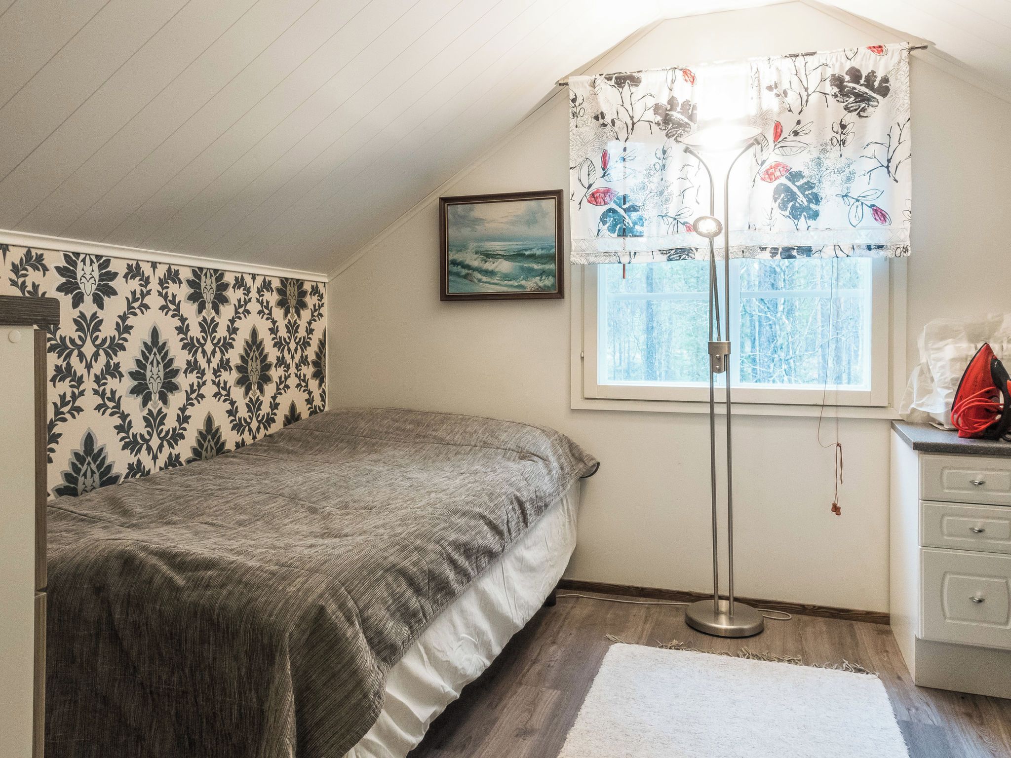 Quarto com cama, janela com cortinas, um quadro na parede e abajur.