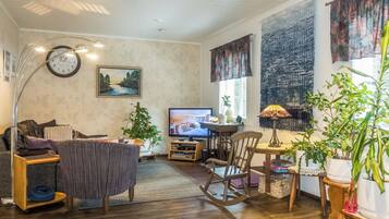 Sala de estar com televisão, relógio e uma grande janela.