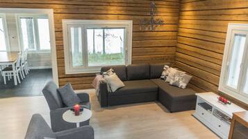 Un salon chaleureux avec un canapé d’angle, une petite table sur laquelle est posée une bougie et une cheminée.