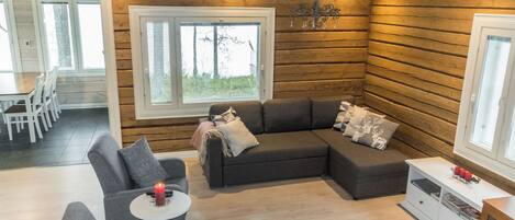 Uma sala de estar acolhedora com um sofá modular, uma mesinha com uma vela e uma lareira.