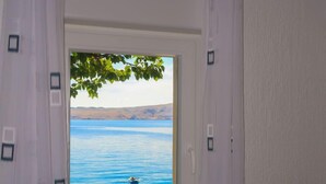 A window with a view of a calm lake and a swimmer. - Bajadera by Interhome (Jablanac)