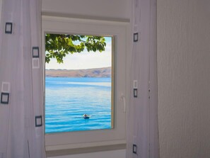 A window with a view of a calm lake and a swimmer. - Bajadera by Interhome (Jablanac)