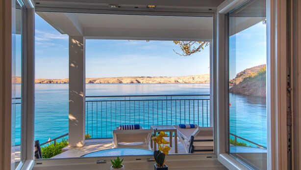 A balcony with a view of the sea and cliffs. There are chairs and a table on the balcony. - Bajadera by Interhome (Jablanac)