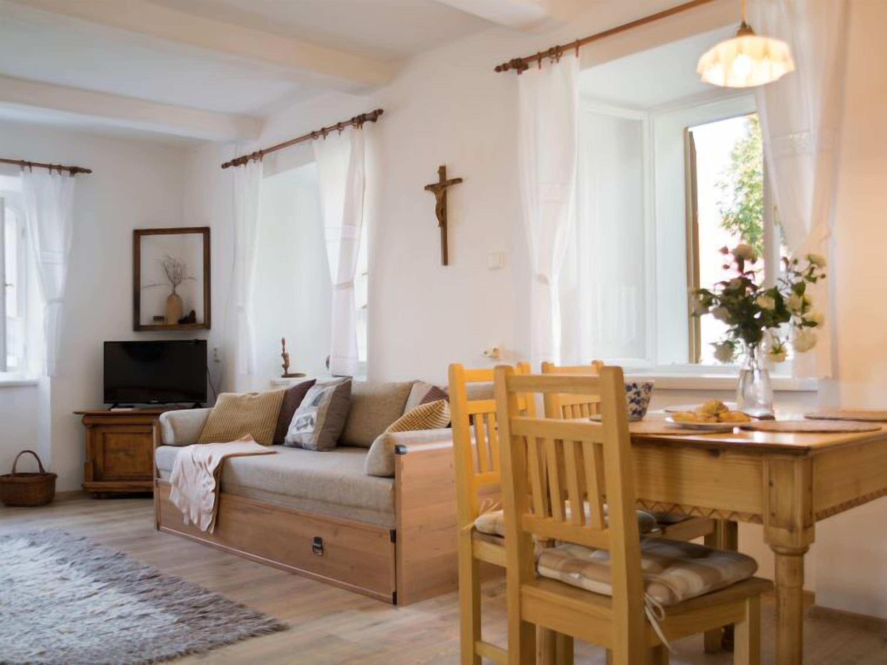 A cozy room with a sofa, wooden dining table, and a TV.