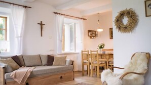 A cozy living room with a sofa, a fluffy chair, a dining table with chairs, and a cross on the wall. - Vacation home Libel by Interhome (Libel)