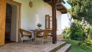 A patio with stone flooring, two wicker chairs, a table, and a vase with flowers. - Vacation home Libel by Interhome (Libel)
