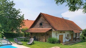 A rustic house with a stone foundation, a red-tiled roof, and a swimming pool with lounge chairs. - Vacation home Libel by Interhome (Libel)