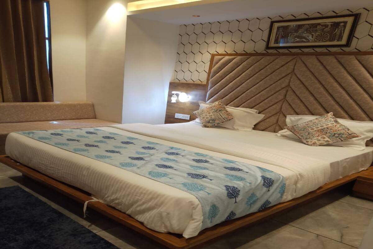 Una habitación de hotel moderna con una cama grande, un cabecero de diseño geométrico y un adorno de pared decorativo.