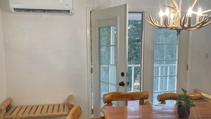 Een eetgedeelte met een houten tafel en stoelen, een bank en een kroonluchter.