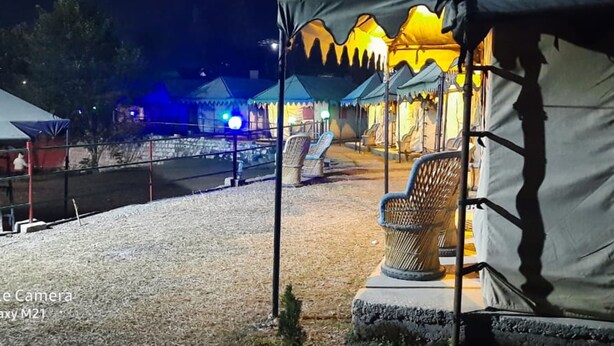 A campsite with tents and a chair. - Camp Awara Rishikesh (Narendranagar)
