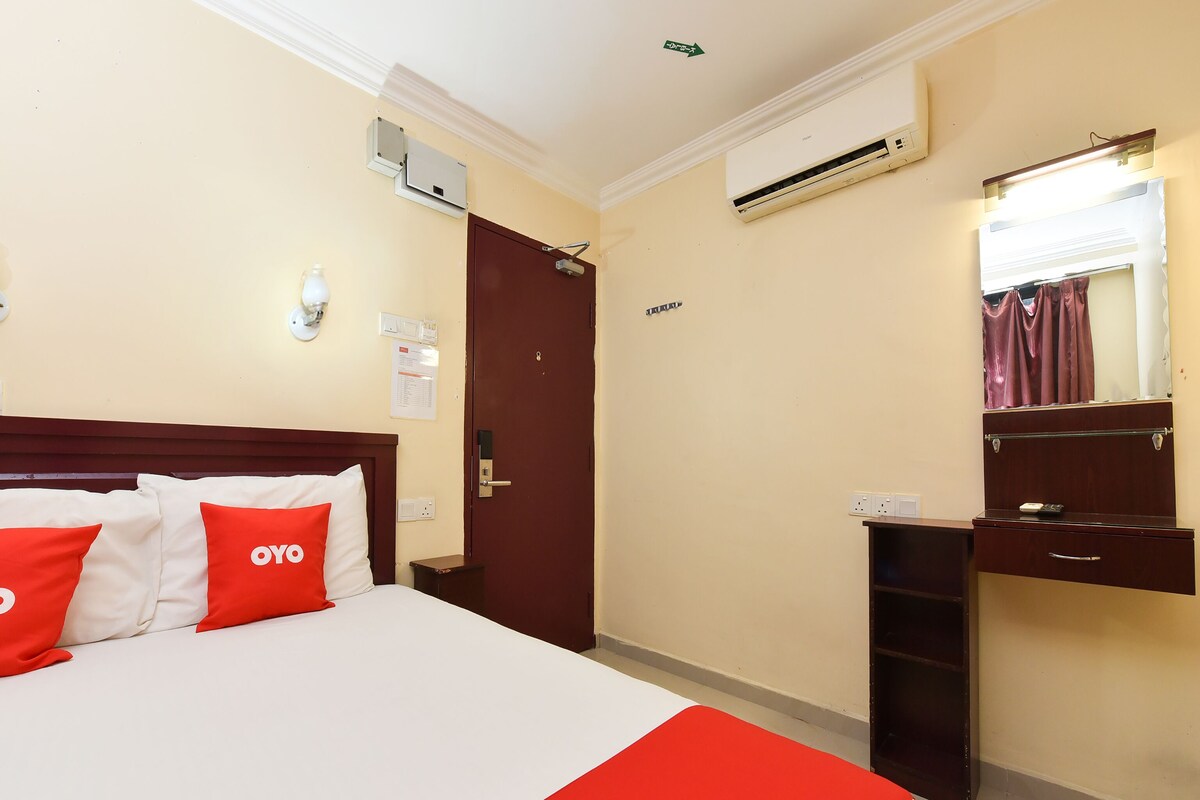 Una habitación de hotel con una cama, un escritorio, un aire acondicionado y un espejo.