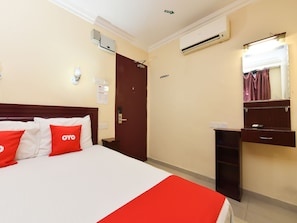 Una habitación de hotel con una cama, un escritorio, un aire acondicionado y un espejo.