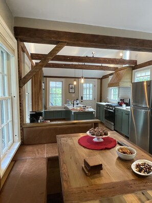 A kitchen with wooden beams, a central island, and a dining table with food. - Historic Downtown Hudson Home (Hudson)