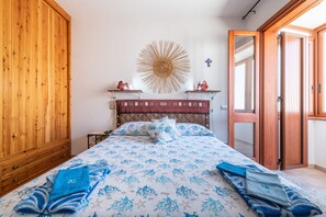 A bedroom with a bed, wooden wardrobe, wall decor, and a door.