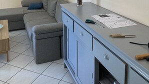 Ett modernt vardagsrum med en grå soffa, ett litet bord med en vas och ett skåp.