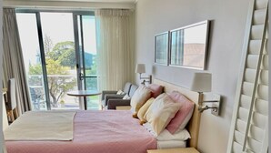 A hotel room with a large bed, a sitting area with a table and chairs, a bathtub, and a large window offering a view of the outdoors. - Spa Retreat Ballina - Your own private spa to enjoy - FREE Wi-Fi (Ballina)