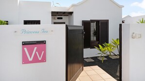 Un bâtiment blanc avec une enseigne indiquant « Princess Ico » et une enseigne rose avec les inscriptions « VV » et « VIVINDAS VACACIONALES ».