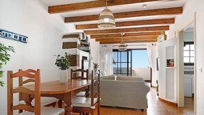 Un espace repas avec des meubles en bois, un luminaire suspendu et une vue sur l’extérieur.