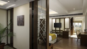 A modern hotel room with a bed, desk, TV, and a large window. - Cygnett Inn Paras (Dehradun)