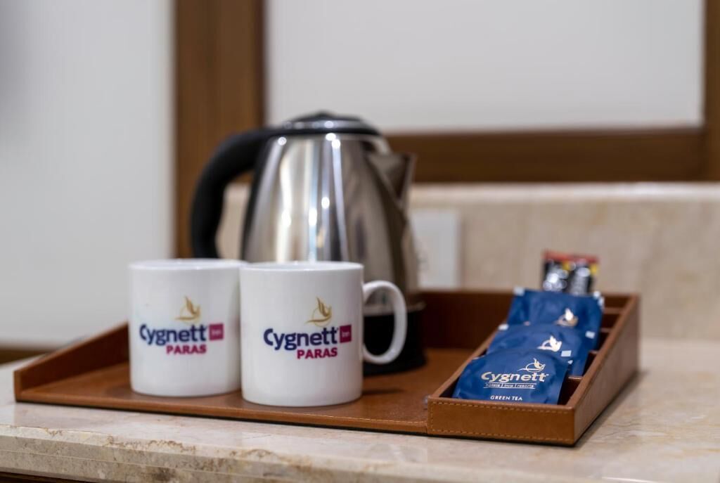 Two mugs with the Cygnett logo, a kettle, and a tray with Cygnett tea packets.