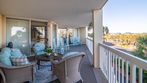 A balcony with wicker furniture, a table, and chairs. - Ocean Oasis Fordham 101 3BR Villa Ocean Views (Pawleys Island)