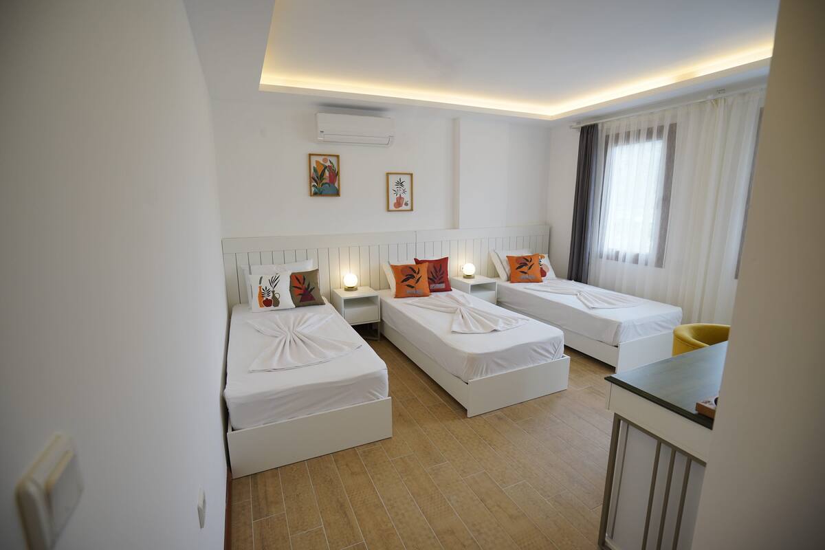 Une chambre d’hôtel avec deux lits simples, un petit bureau et une fenêtre avec des rideaux.