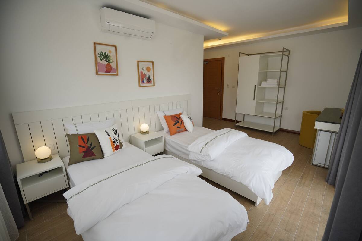 Une chambre d’hôtel avec deux lits, une armoire, un bureau et une salle de bain.