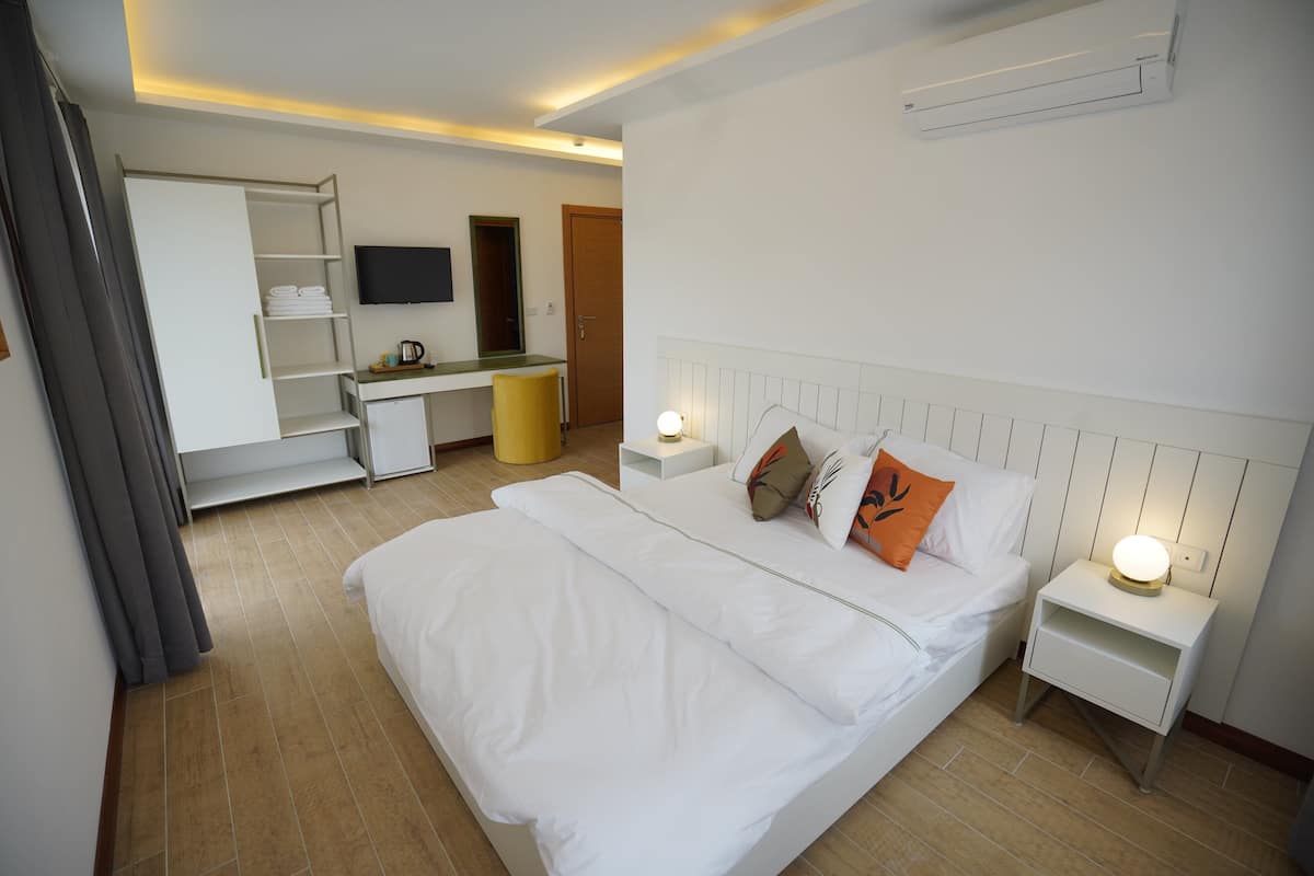 Une chambre d’hôtel équipée d’un lit, de tables de chevet, d’un bureau, d’une chaise, d’un téléviseur et d’un appareil de climatisation.