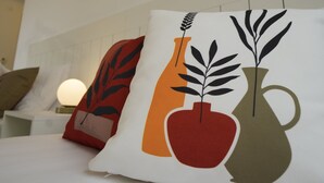 A neatly made bed with decorative pillows, a bedside table with a lamp, and wall-mounted artwork. - Mons Casa Boutique Hotel (Marmaris)
