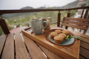 Een houten tafel met een dienblad waarop muffins en twee mokken staan.
