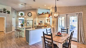 A modern kitchen with a central island, wooden dining table, and bar stools. - Pool, Putting Green, Fire Pit: Elegant Peoria Home (Peoria)