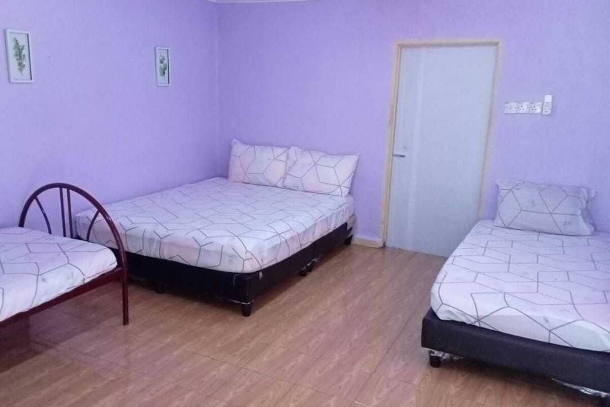 Une pièce avec trois lits disposés dans un coin, une porte et une chaise.