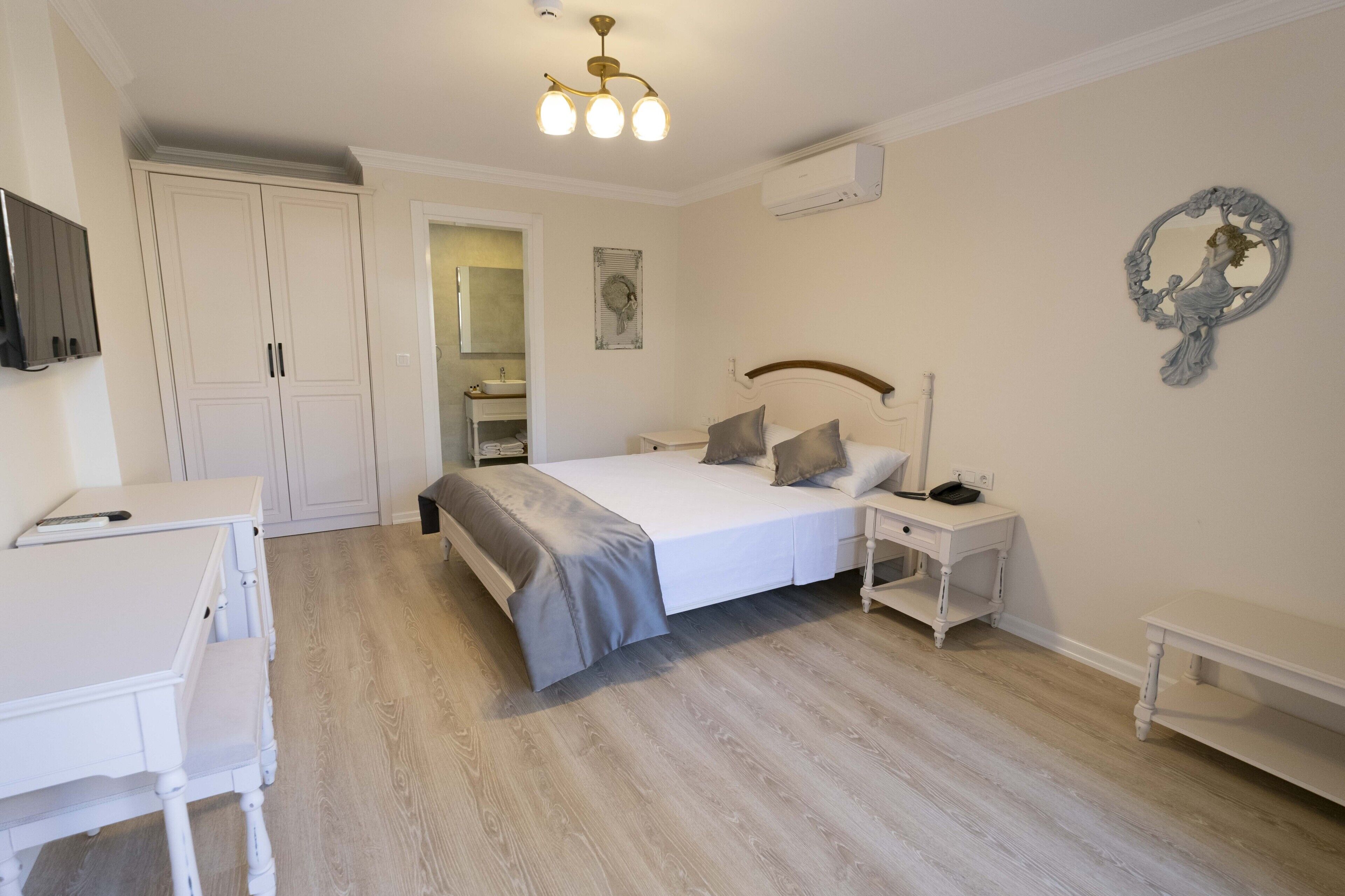 A bedroom with a bed, bedside tables, a desk, and a wardrobe.